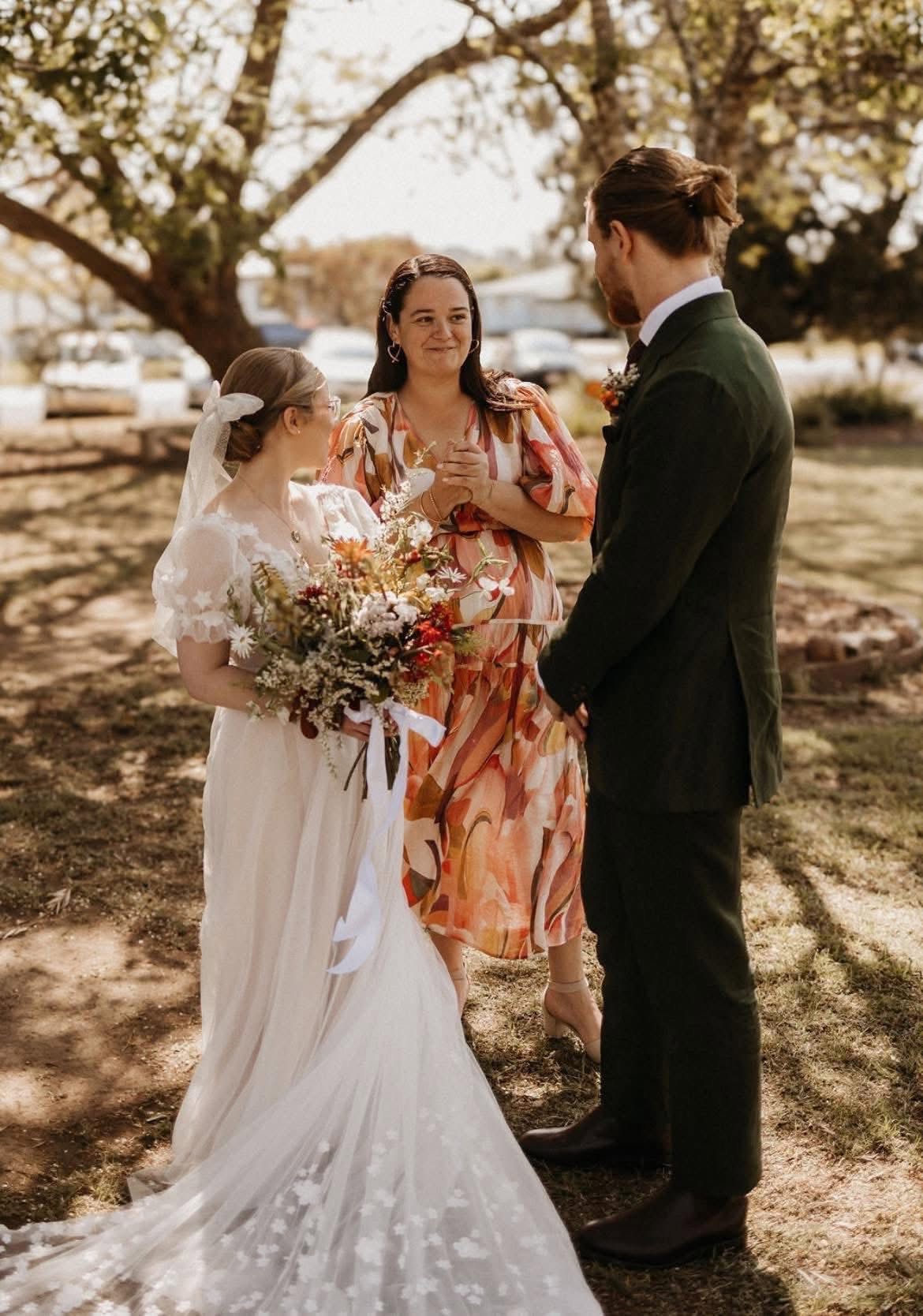 Simone officiating an outdoor country wedding ceremony beneath a shady gum tree